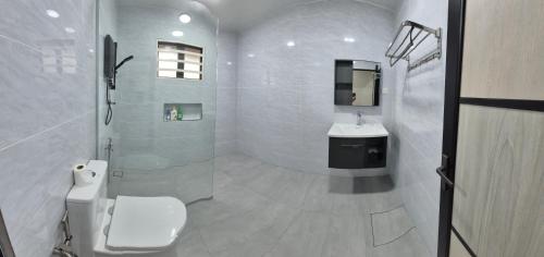 a white bathroom with a toilet and a sink at Hatasan Homestay Guess House in Perai