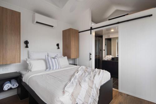 a bedroom with a large bed with white sheets at Grevillea Villa in Valdora