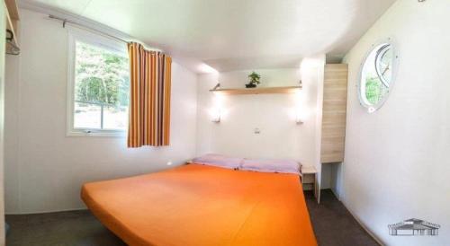 an orange bed in a small room with a window at Camping 3 étoiles - Parc aquatique - ccbbaia 