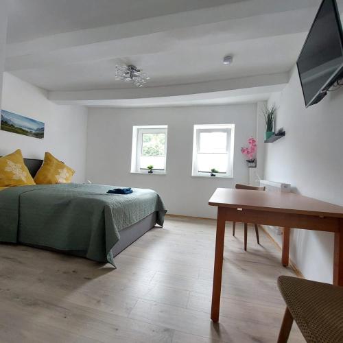 a bedroom with a bed and a table and two windows at Hotel Silonce Bilstein in Lennestadt