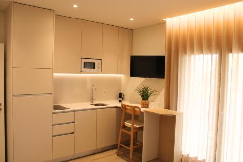 a small kitchen with white cabinets and a table at ma-la studios Guimarães in Guimarães