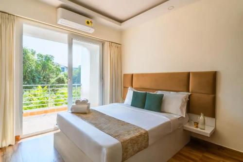 Un dormitorio con una cama grande con una ventana grande. en Luxury Apartments Candolim Luxfort, en Candolim