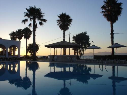 a swimming pool with palm trees and a gazebo at Andromeda Hotel Apartments in Kos Town