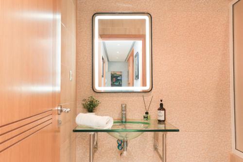 a bathroom with a glass sink and a mirror at Ocean View Apartment by Hilton & TGV Station in Tangier