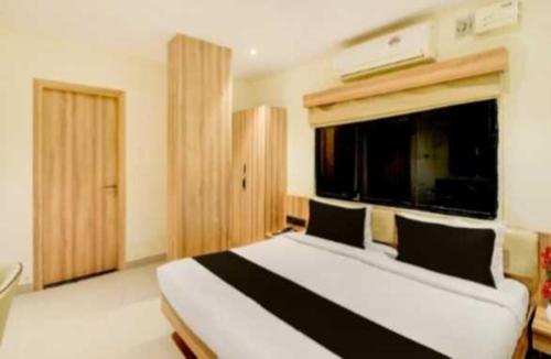 a bedroom with a white and black bed with a window at Hotel O Malani Inn in Kukatpalli