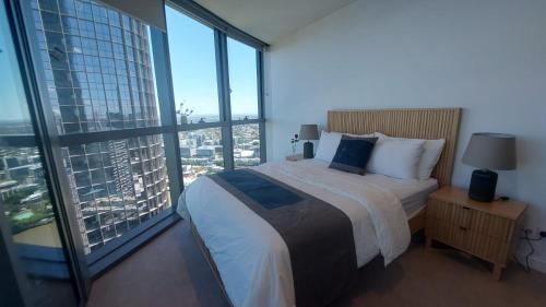 ein Schlafzimmer mit großem Bett und großen Fenstern in der Unterkunft Luxury Riverfront Apartment level 38 Queen's Wharf Tower in Brisbane