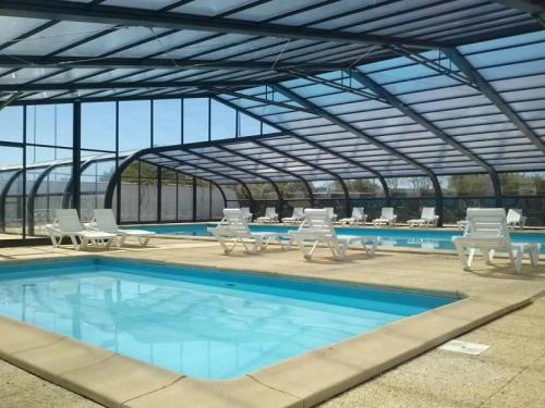 a large swimming pool with chairs and tables in a building at ZEcamping 3 étoiles familial animaux acceptés piscine couverte et chauffée in Saint-Hilaire-de-Talmont