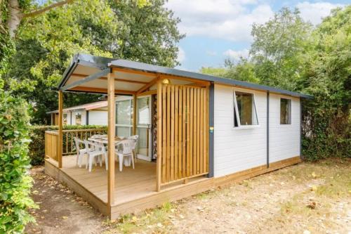 a small cabin with a table on a deck at ZEcamping 3 étoiles familial animaux acceptés piscine couverte et chauffée in Saint-Hilaire-de-Talmont