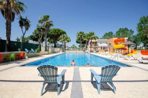a pool at a resort with two chairs and a person swimming at Camping 4 étoiles - Piscine - ccbbecd in Le Grau-dʼAgde
