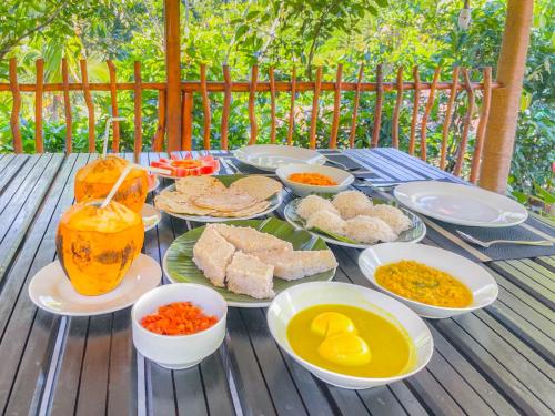 une table avec des assiettes et des bols de nourriture dans l'établissement Sinharaja Rainforest Vibe, à Deniyaya