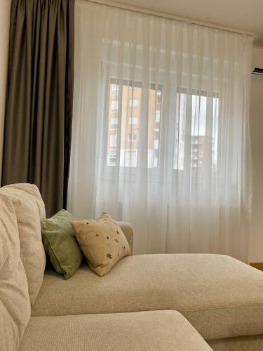 - un canapé avec des oreillers installé devant une fenêtre dans l'établissement FILIP Lux Apartman sa garažom, à Doboj
