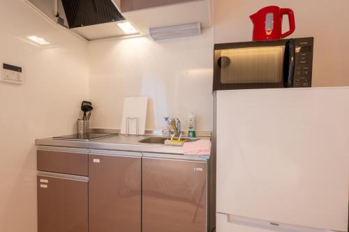 una piccola cucina con frigorifero e forno a microonde di O's Apartment Hotel In Kyobashi 3FB ad Osaka