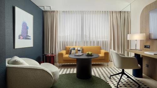 a living room with a yellow couch and a table at InterContinental Athenaeum Athens by IHG in Athens