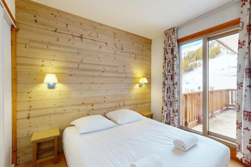 - une chambre avec un mur en bois, un lit et une fenêtre dans l'établissement Les Arolles - La Plagne 1800, à La Plagne Tarentaise