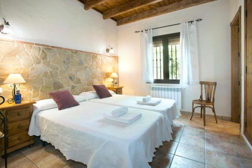 une chambre avec deux lits, une table et une chaise dans l'établissement El Nogal, à Arriate