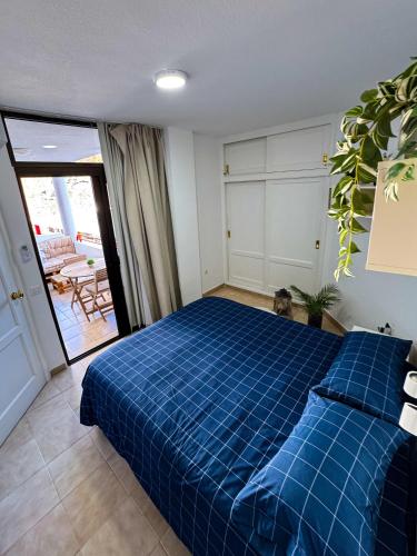 a bedroom with a blue bed and a patio at Apartamento Victoria in Mogán