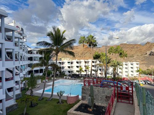 ein Resort mit einem Pool, Palmen und Gebäuden in der Unterkunft Apartamento Victoria in Mogán