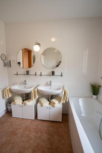a bathroom with two sinks and a tub and mirrors at Chalet Olympia in Neustift im Stubaital