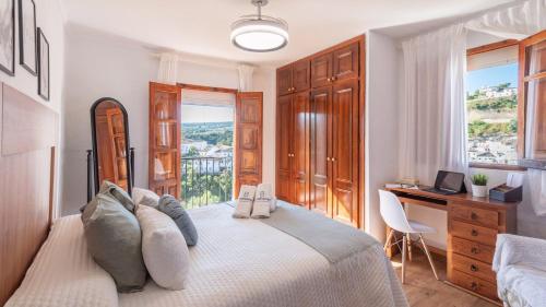 a bedroom with a bed with a desk and a computer at Los Cortinales Setenil de las Bodegas by Ruralidays in Setenil