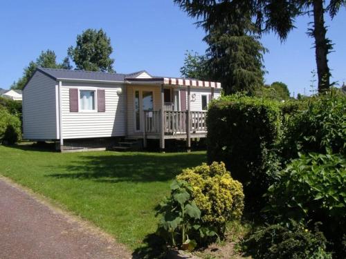 a small white house with a porch in a yard at ZEcamping 4 étoiles familial avec étang de pêche et piscine chauffée in La Haye-du-Puits