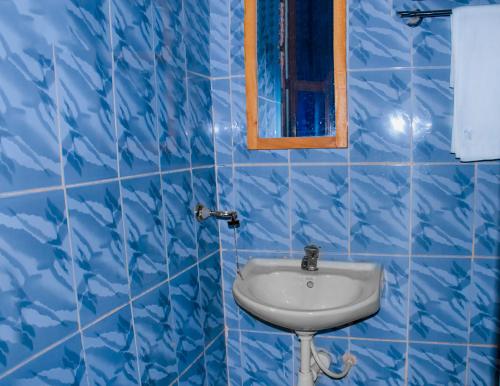 bagno piastrellato blu con lavandino e specchio di Biez Homestay a Karatu