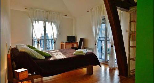 a bedroom with a bed with green pillows and a balcony at Lou Lombrès in Lombrès