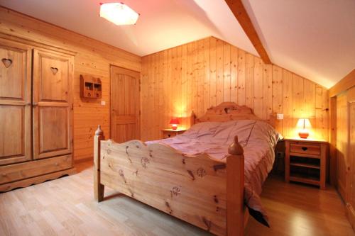 une chambre avec un grand lit dans une pièce aux murs en bois dans l'établissement Le Chalet Vert entre nature et animations, à La Bresse