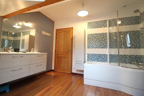 une salle de bain avec une baignoire, un lavabo et un miroir dans l'établissement Le Chalet Vert entre nature et animations, à La Bresse