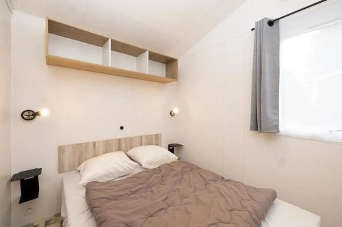 une petite chambre avec un lit et une fenêtre dans l'établissement Camping 3 étoiles - Piscine - ccbb0if, à Montpon-Ménestérol