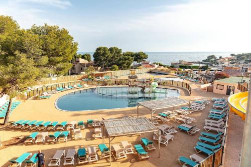 - une vue sur la piscine avec des chaises longues et l'océan dans l'établissement Bungalow proche mer CARRY LE ROUET, à Carry-le-Rouet