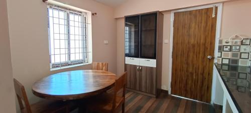 科代卡纳尔Raja Home Stay的一间带木桌和窗户的用餐室