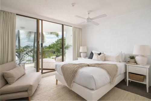 ゴールドコーストにあるPalms on Gold - Sun, Swims & Riverside Viewsのベッドと椅子のある白い寝室