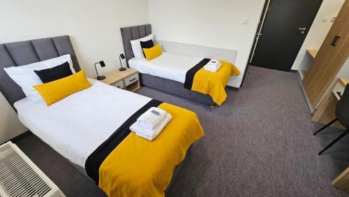two beds in a room with yellow and white sheets at MOSiR Rypin in Rypin