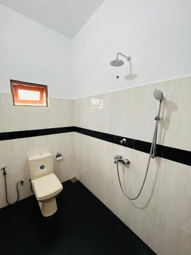 a bathroom with a toilet and a shower at Yala Mangora Inn in Tissamaharama