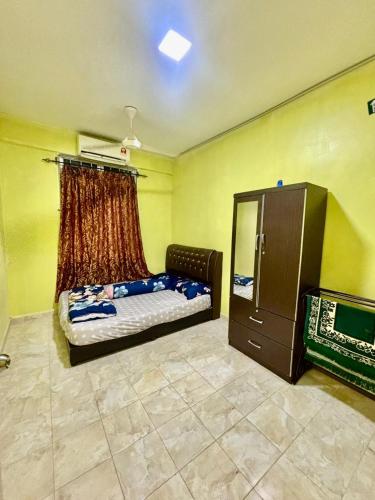 ein Schlafzimmer mit einem Bett und einer Kommode darin in der Unterkunft Homestay Abah Wakaf Che Yeh in Kota Bharu