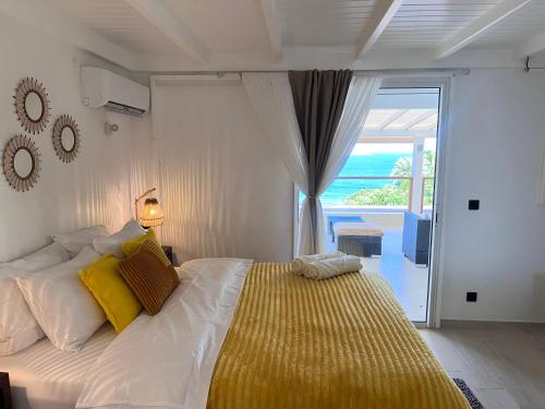 Una cama blanca con almohadas amarillas en un dormitorio. en Casa dulce - Camaruche, en Saint Barthelemy
