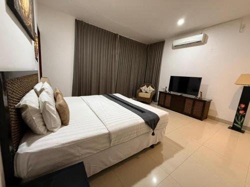 a bedroom with a large bed and a television at Villa Rob in Kerobokan