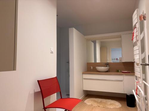 a bathroom with a red chair and a sink at Appartement Les Marguerites spa et spa de nage in Contrexéville
