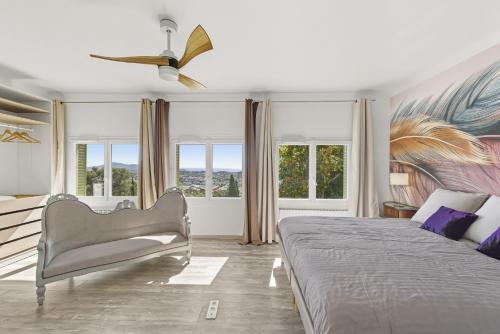 a bedroom with a bed and a chair and windows at Villa vue mer panoramique & piscine chauffée in Toulon