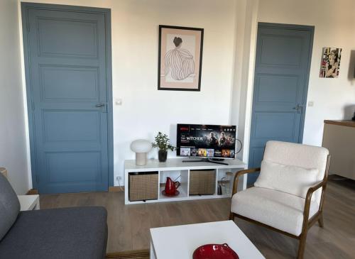 un salon avec deux portes bleues et une télévision dans l'établissement Les Capucines, comme chez soi, loin de chez soi, à Aubenas