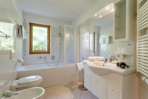 a white bathroom with a sink and a tub and a toilet at Villa Bernhard in Siusi