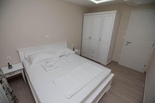 Villa Rita Apartments I في بروماجنا: غرفة نوم بيضاء مع سرير أبيض وخزانة بيضاء
