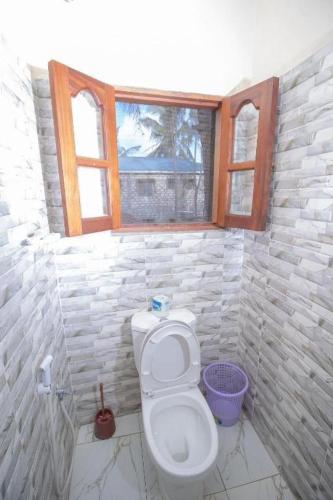 a bathroom with a toilet and two windows at GK Palm Resort Watamu in Watamu