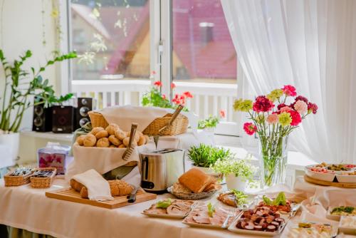 een tafel met eten, brood en bloemen erop bij Geovita Krynica-Zdroj in Krynica Zdrój