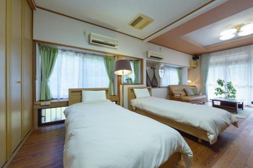 a hotel room with two beds and a chair and window at ようこそ月の宿へ in Shindembaru