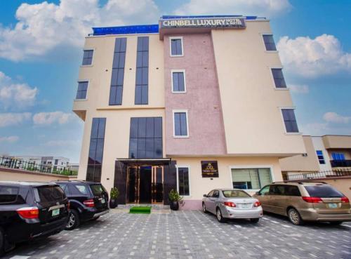 un grand bâtiment avec des voitures garées dans un parking dans l'établissement Chinbell Luxury Hotel & Suites, à Wamba
