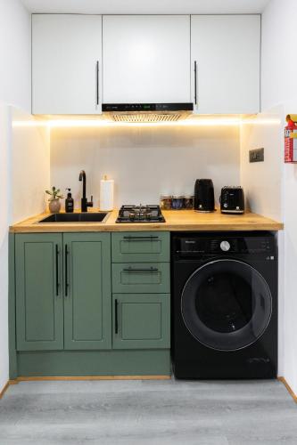 a kitchen with green cabinets and a washing machine at Cosy 1 Bedroom Studio with King Bed Kitchenet in Central Kathmandu with Terrace in Kathmandu