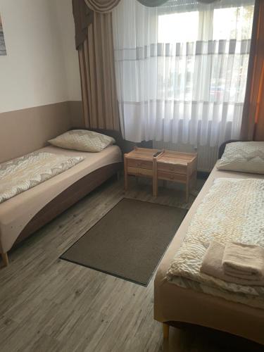 a bedroom with two beds and a table and a window at LIVI Hostel und Pension in Dortmund