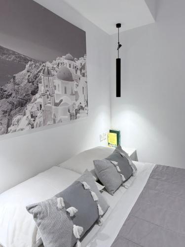 Ein Schlafzimmer mit einem großen weißen Bett und einem Gemälde an der Wand in der Unterkunft Fira Basement Studios in Fira