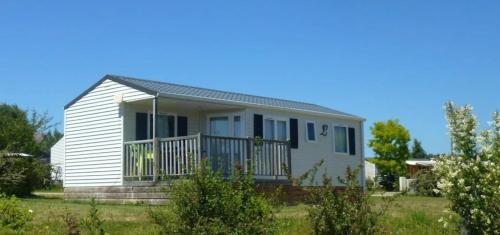 a white house with a porch and a balcony at ZEcamping 3 étoiles dog friendly bien-être piscine au bord dun lac in Loudéac